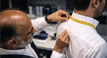 A tailor measuring the shoulder of a white shirt